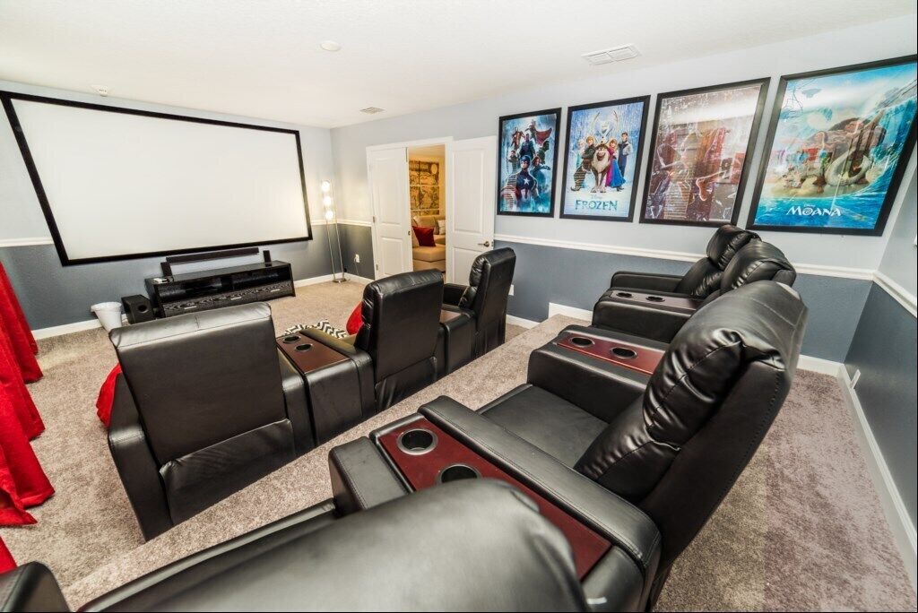 Un home theater con un grande schermo, poltrone in pelle e manifesti cinematografici alle pareti.