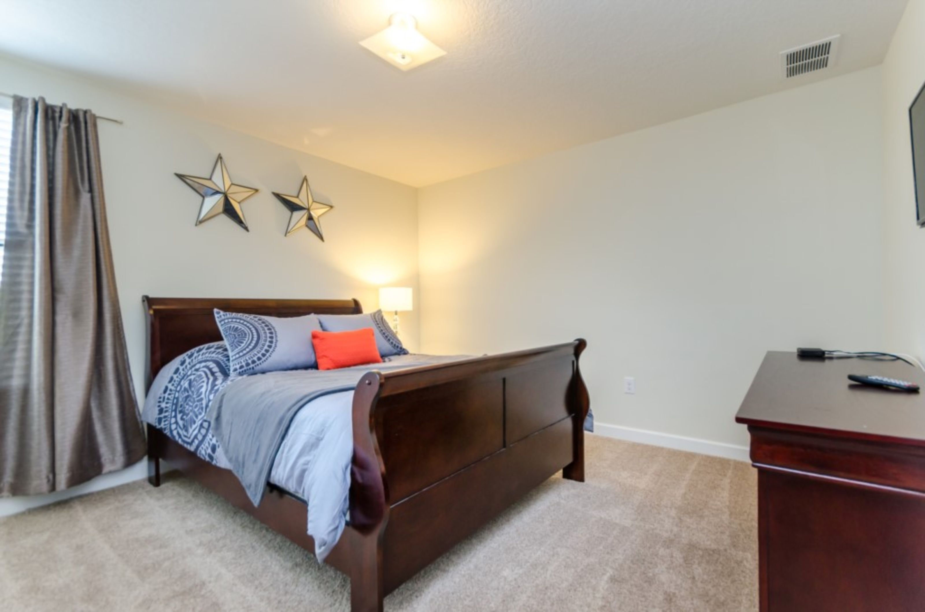 A bedroom with a wooden bed, a desk, and two star-shaped wall decorations.