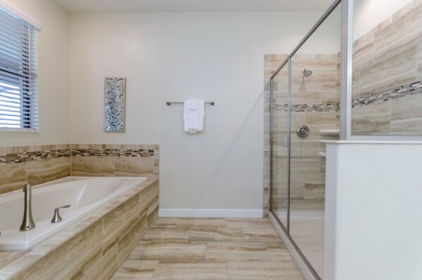 A modern bathroom with a glass-enclosed shower, a freestanding bathtub, and a tiled backsplash.
