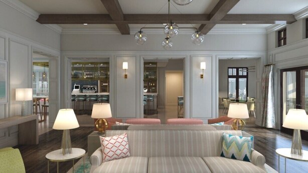 A spacious living room with a sofa, two lamps, and a bar area in the background.