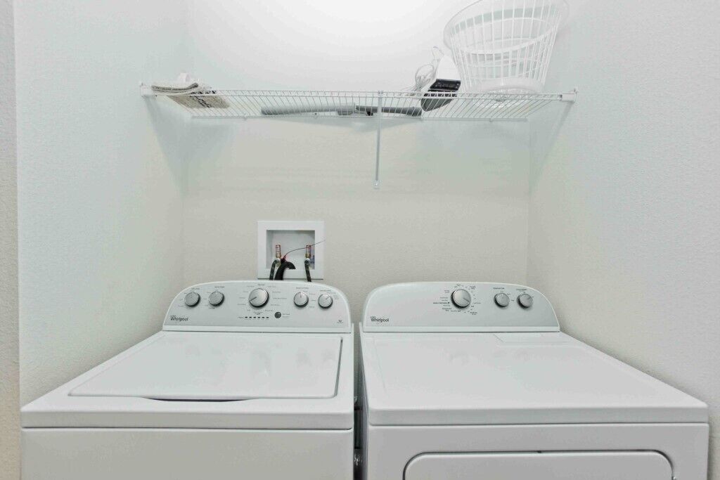 Ein Waschraum mit zwei Whirlpool-Waschmaschinen und einem weißen Korb auf einem Regal.
