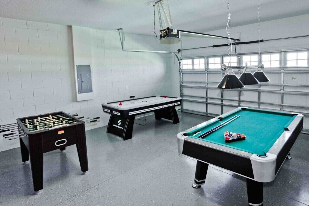 Una sala ricreativa con un tavolo da calcio, un tavolo da biliardo e un proiettore.