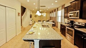 A modern kitchen with granite countertops, stainless steel appliances, and a central island. - Luxury 5 Bedroom Private Pool IHR 1019 (Kissimmee)