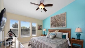 A bedroom with a bed, two bedside tables, a ceiling fan, and a window with blinds.
