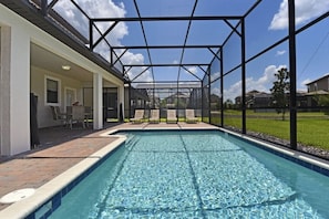 A swimming pool with a covered patio area, lounge chairs, and a view of the neighborhood. - Champions Gate IHR 3017 (Davenport)