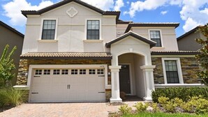 A two-story house with a garage, stone facade, and a well-maintained lawn.