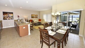 A spacious kitchen with a dining area, featuring a large island, modern appliances, and a view to the outside.