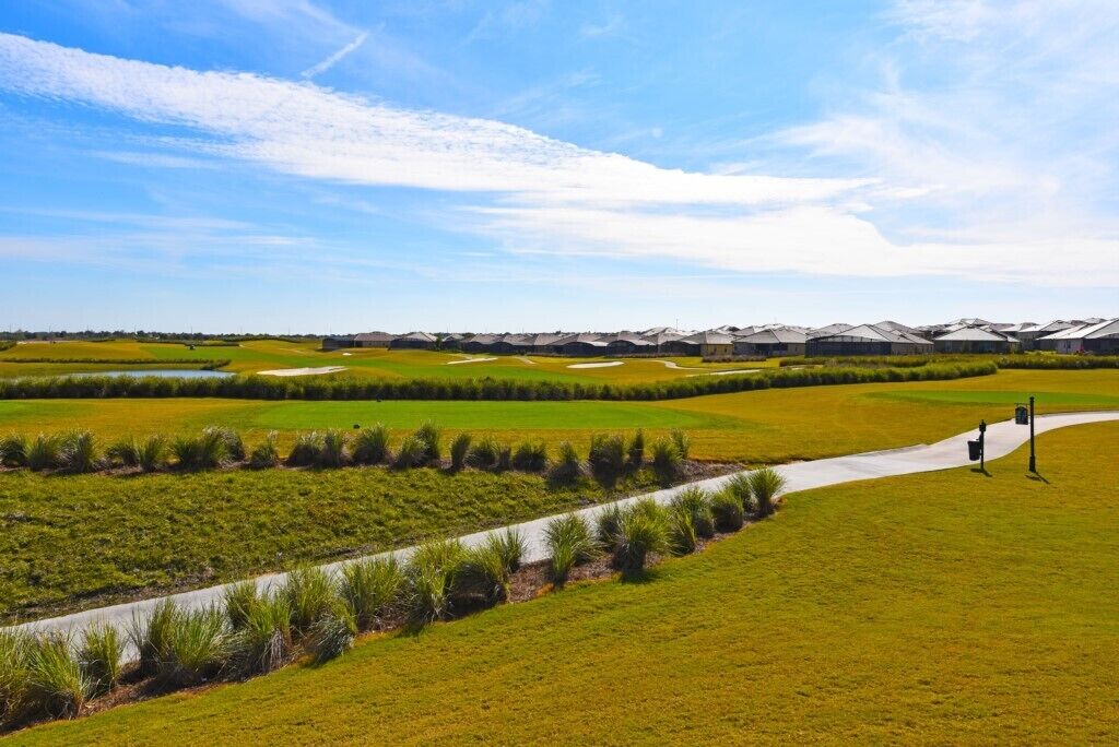 A golf course with a clear path, green fields, and distant buildings.