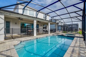 A swimming pool with a glass enclosure, a covered patio area, and a view of the surrounding neighborhood. - Luxury 6 Bed Villa With Saltwater Pool & Spa (Kissimmee)