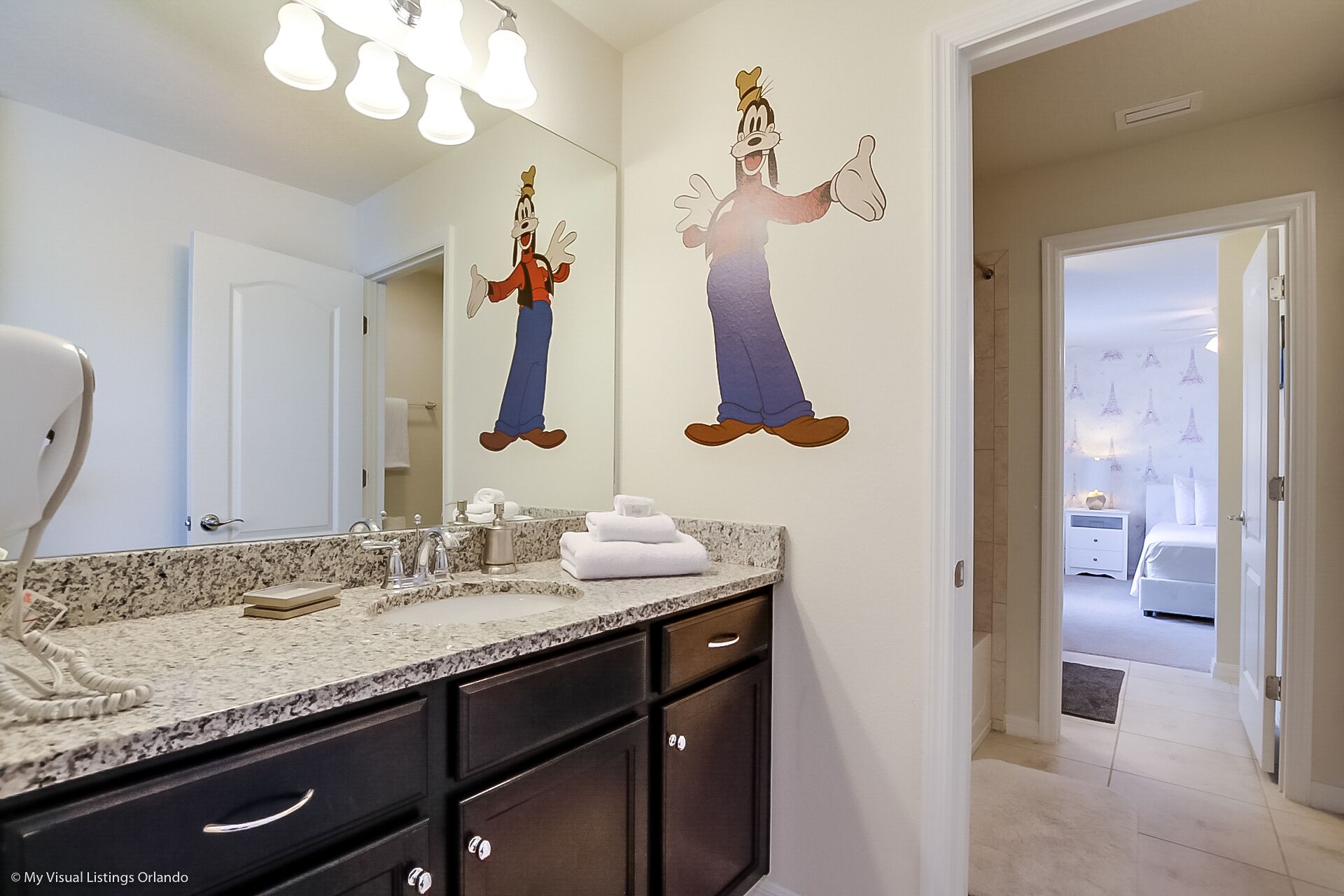 A bathroom with a double sink vanity, a mirror, and a towel rack.