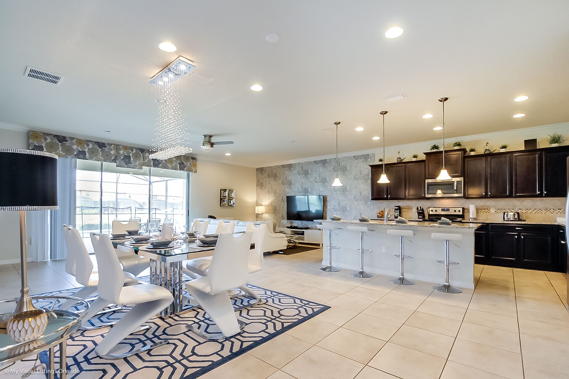 A modern kitchen with a central island, dark cabinets, and a large window.