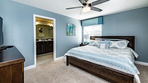 A bedroom with a bed, a ceiling fan, a nightstand, and a desk. - Disney Area 5 Bedroom Private Pool Storey Lake (Kissimmee)