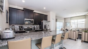 A modern kitchen with dark cabinets, stainless steel appliances, and a granite countertop. - Disney Area 5 Bedroom Private Pool Storey Lake (Kissimmee)