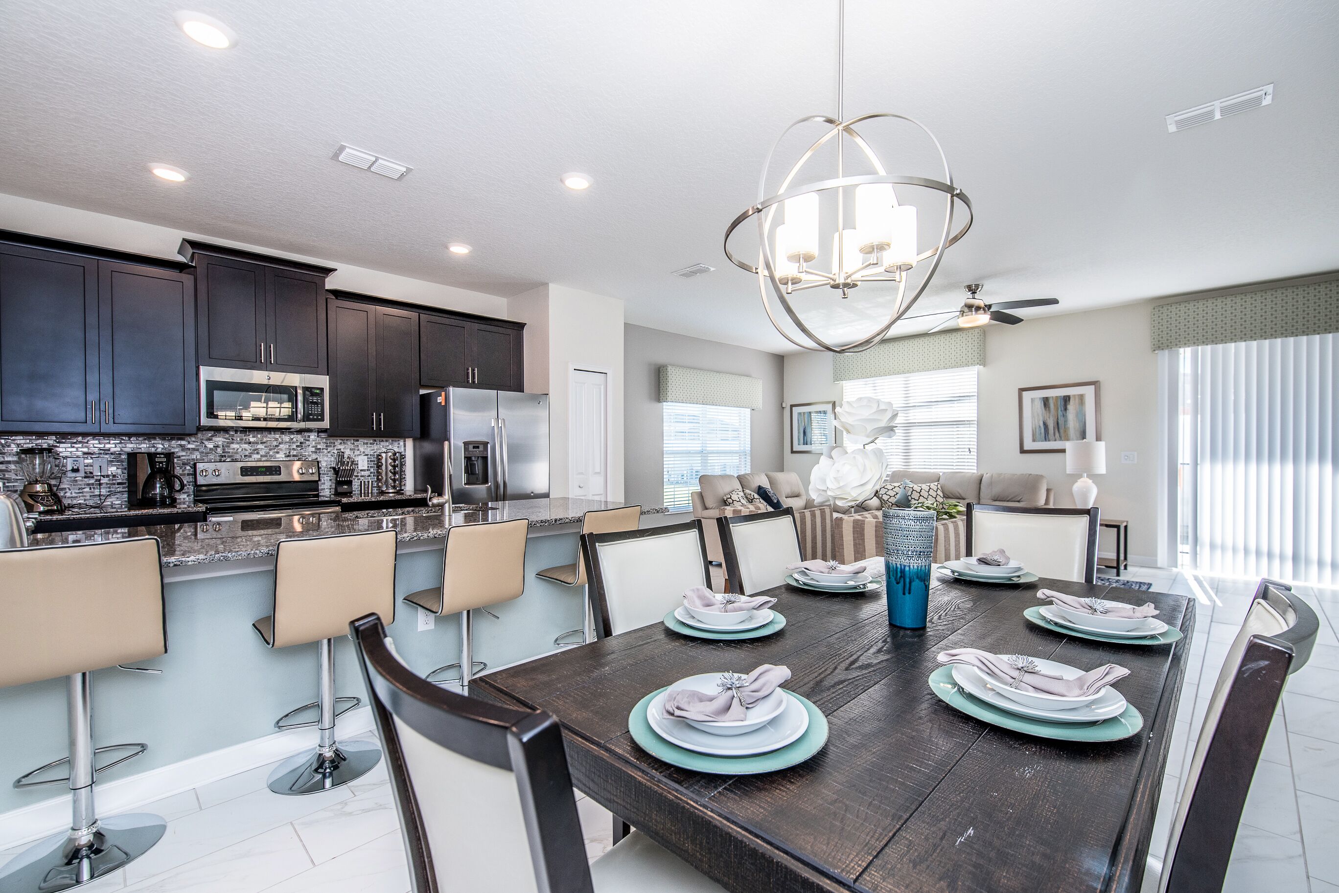 A modern kitchen with dark cabinets, a stainless steel microwave, and a large island with bar stools.
