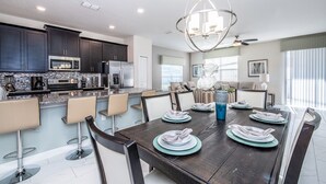 A modern kitchen with dark cabinets, a stainless steel microwave, and a large island with bar stools. - Disney Area 5 Bedroom Private Pool Storey Lake (Kissimmee)