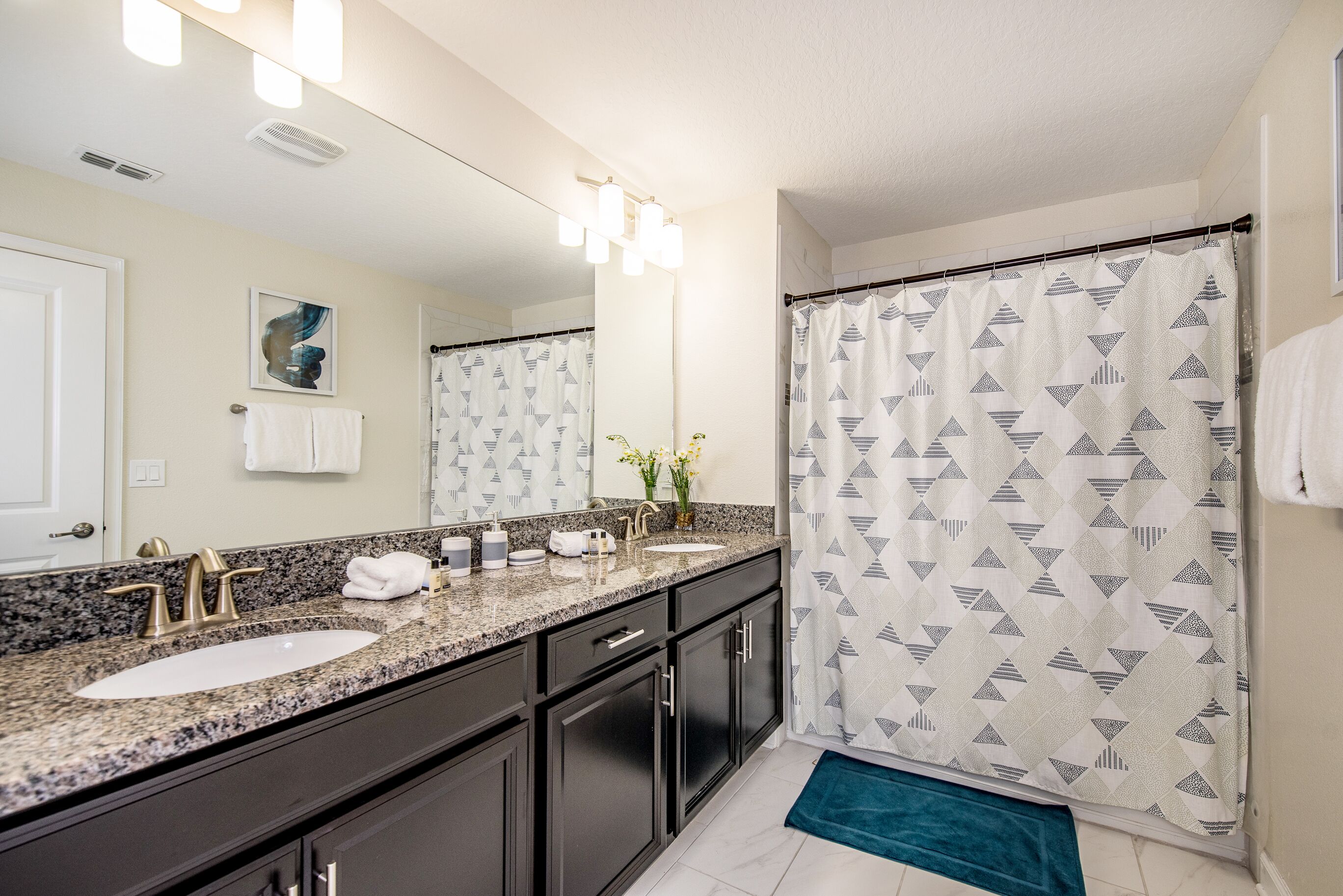 A bathroom with two sinks, a mirror, and a shower curtain.