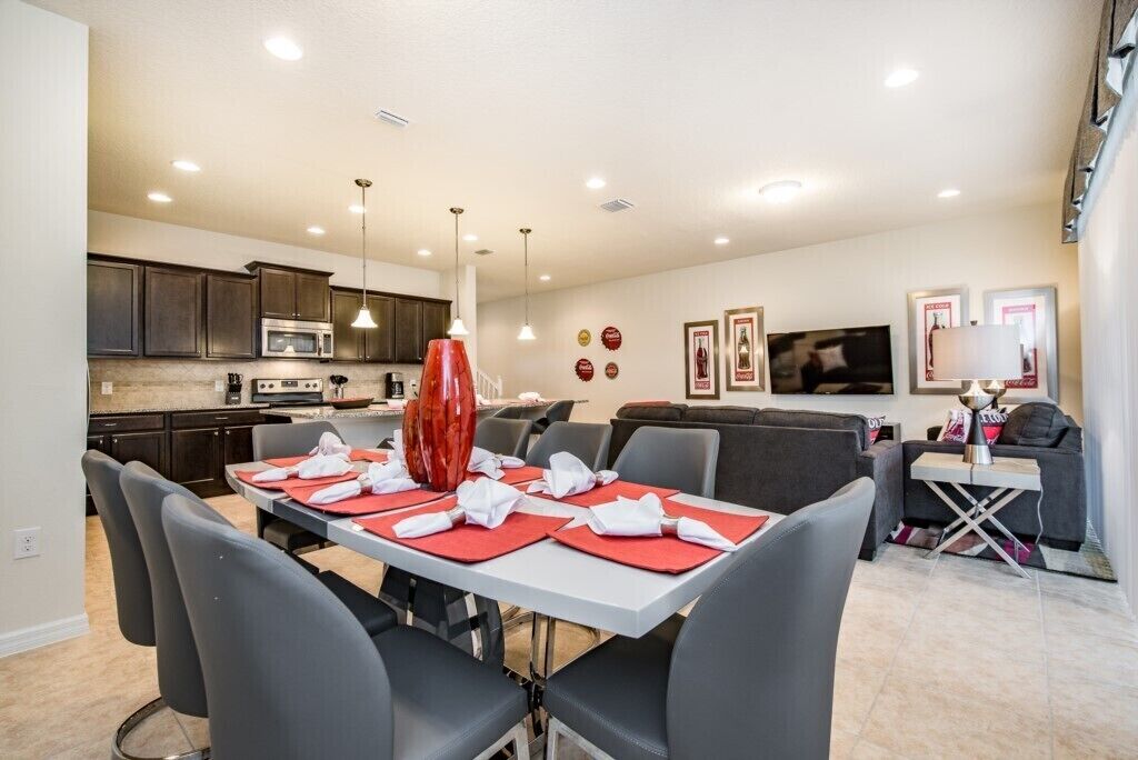 A modern kitchen with dark cabinets, a microwave, and a dining area with a table set for four.