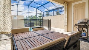 A covered patio with a wooden table and chairs, a grill, and a view of the sky through a glass ceiling. - Summer Special Solara Villa (Kissimmee)