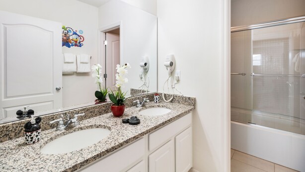 Une salle de bain avec deux lavabos, un grand miroir et une douche.