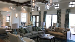 A spacious lobby with a modern chandelier, comfortable seating, and large windows.