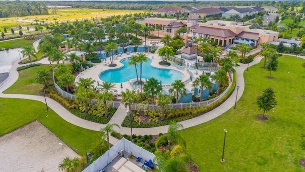 A resort with a central pool, surrounded by palm trees and a well-maintained lawn.