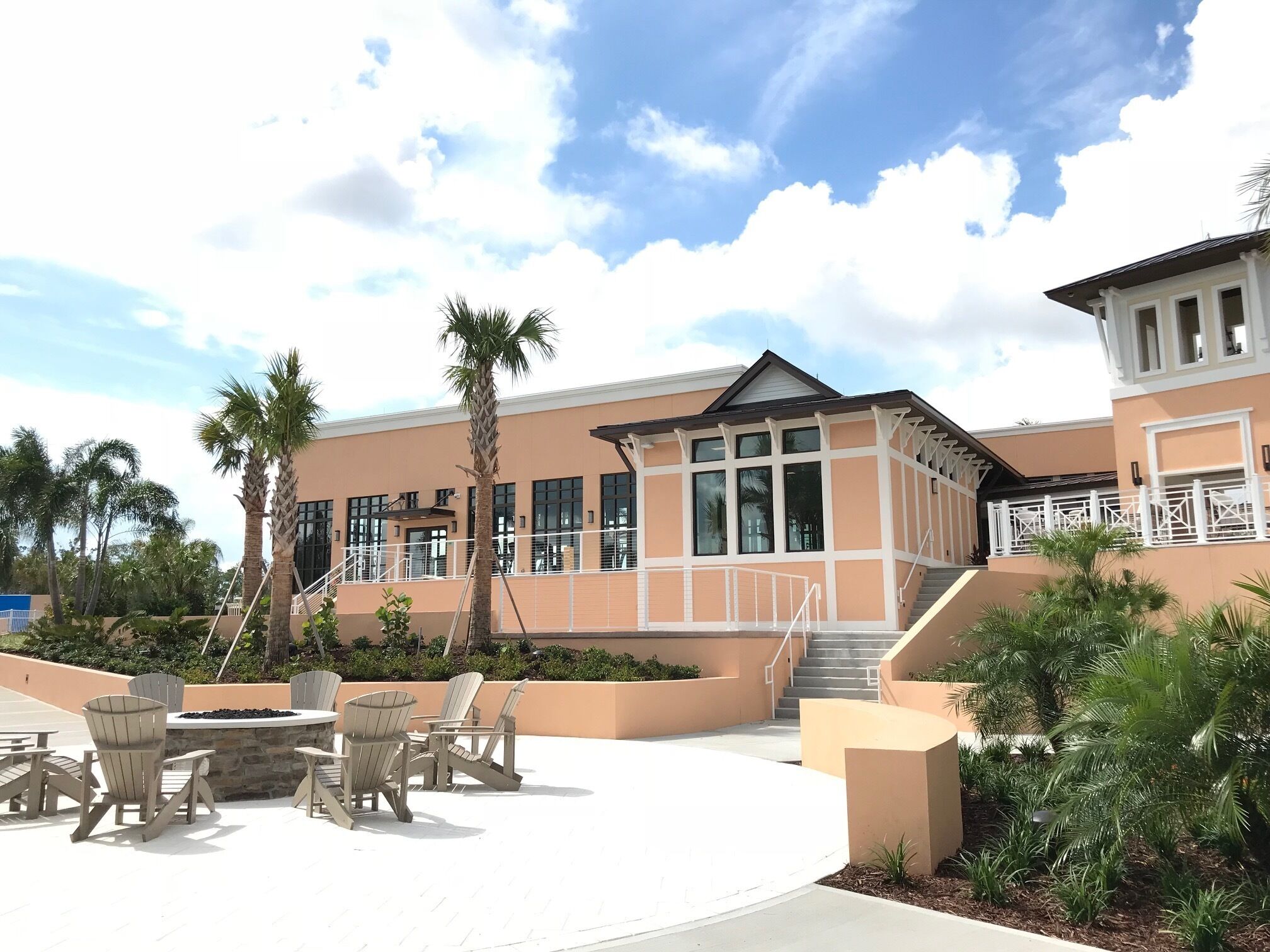A resort with a pool area, outdoor seating, and a building with large windows and a covered section.