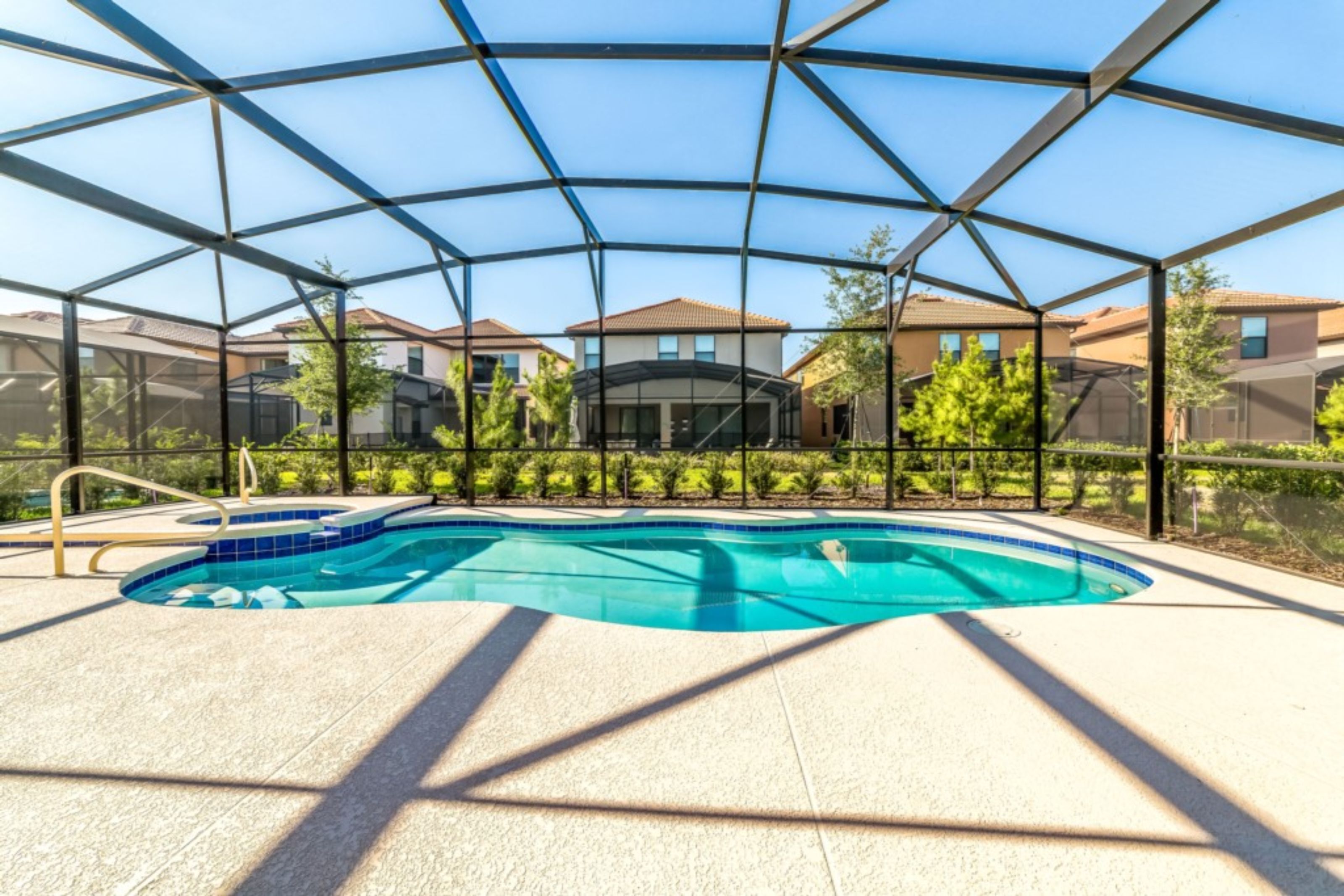 Una piscina con cerramiento de vidrio, rodeada de una valla y edificios residenciales al fondo.