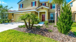 A two-story house with a garage, surrounded by a well-maintained lawn and palm trees. - Solterra - IHR 4066 (Davenport)