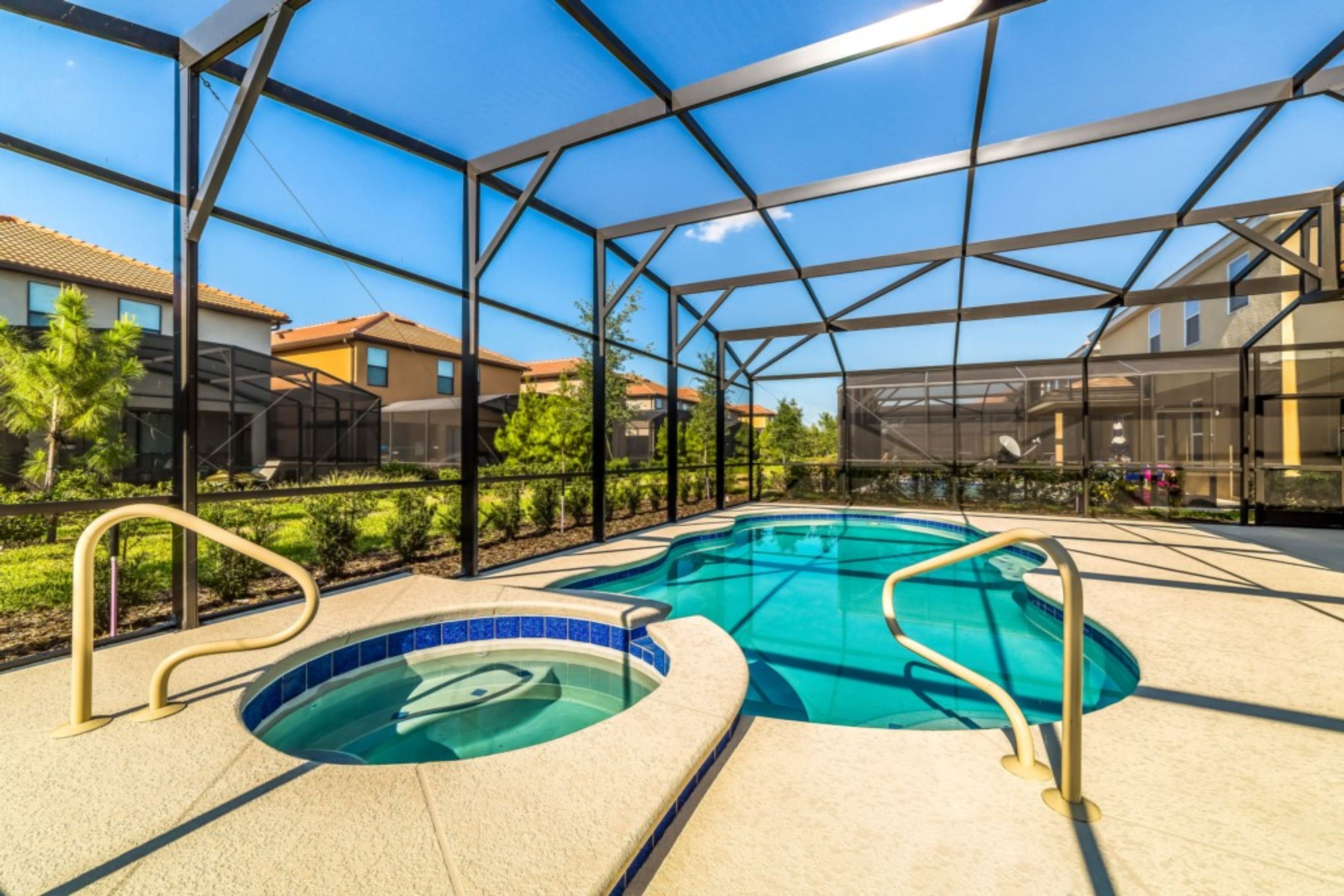 A swimming pool with a glass enclosure, surrounded by a patio area with a clear view of residential buildings in the background.