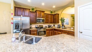 A kitchen with granite countertops, stainless steel appliances, wooden cabinets, and a white door. - Solterra - IHR 4066 (Davenport)