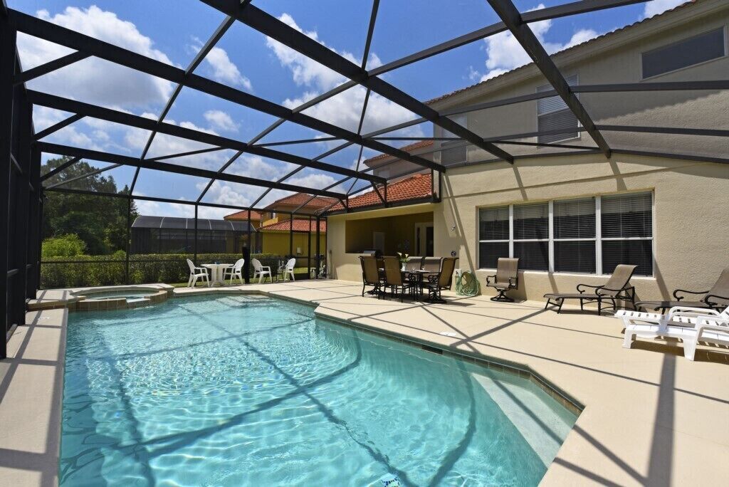 A swimming pool with a glass ceiling, surrounded by lounge chairs and tables.