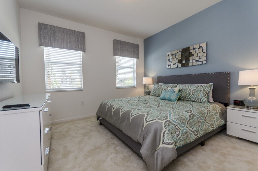 A bedroom with a bed, bedside tables, a dresser, and a wall-mounted artwork.