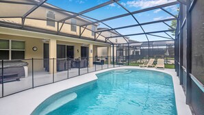 Ein Schwimmbecken mit Glasüberdachung, Sitzgelegenheiten im Freien und einer überdachten Terrasse.