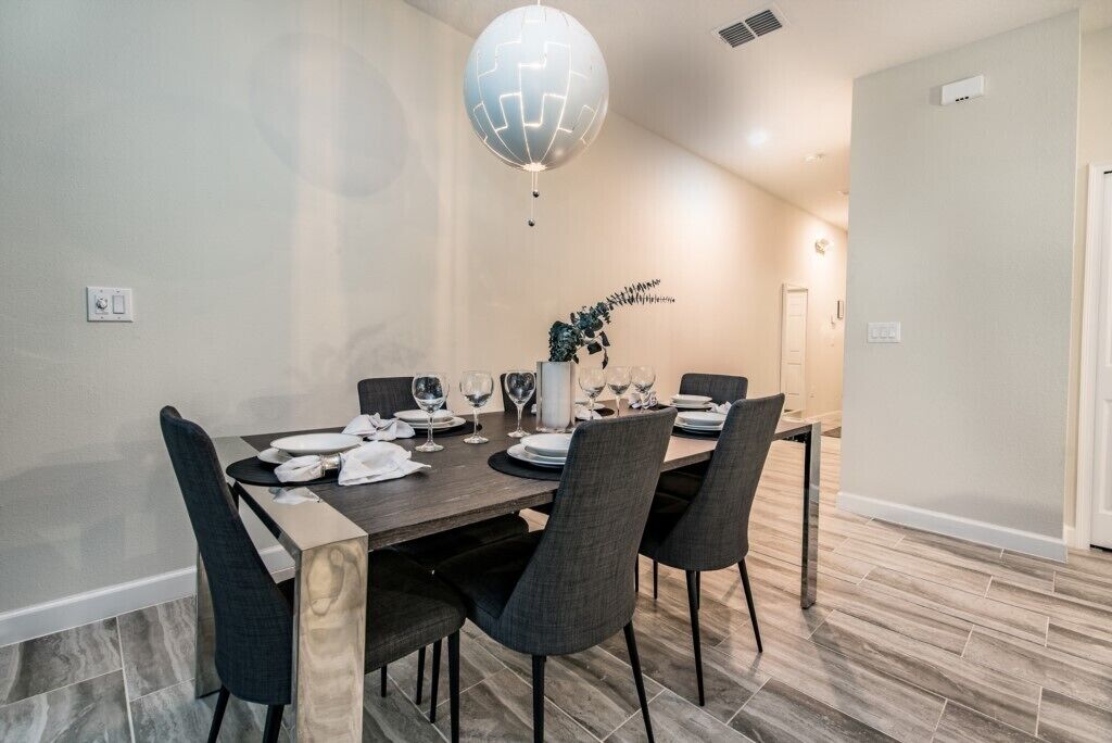 A dining area with a wooden table set for four, surrounded by chairs.
