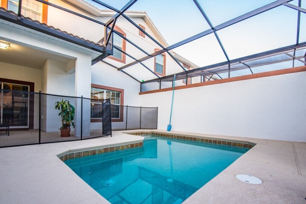 Une piscine intérieure offrant une vue dégagée sur les environs, notamment un balcon doté d’une rambarde et d’un pot de fleurs.
