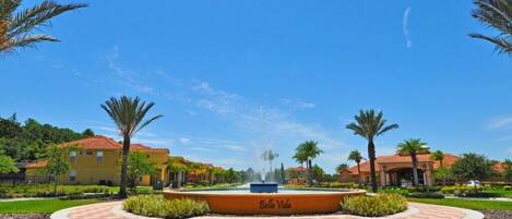 A courtyard with a fountain, palm trees, and a building labeled "Bella Vida".