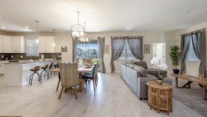 Een ruime woonkamer met een eettafel, bank en een keuken op de achtergrond.
