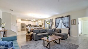 Een ruime woonkamer met een grijze modulaire bank, een houten salontafel en een grijs vloerkleed.