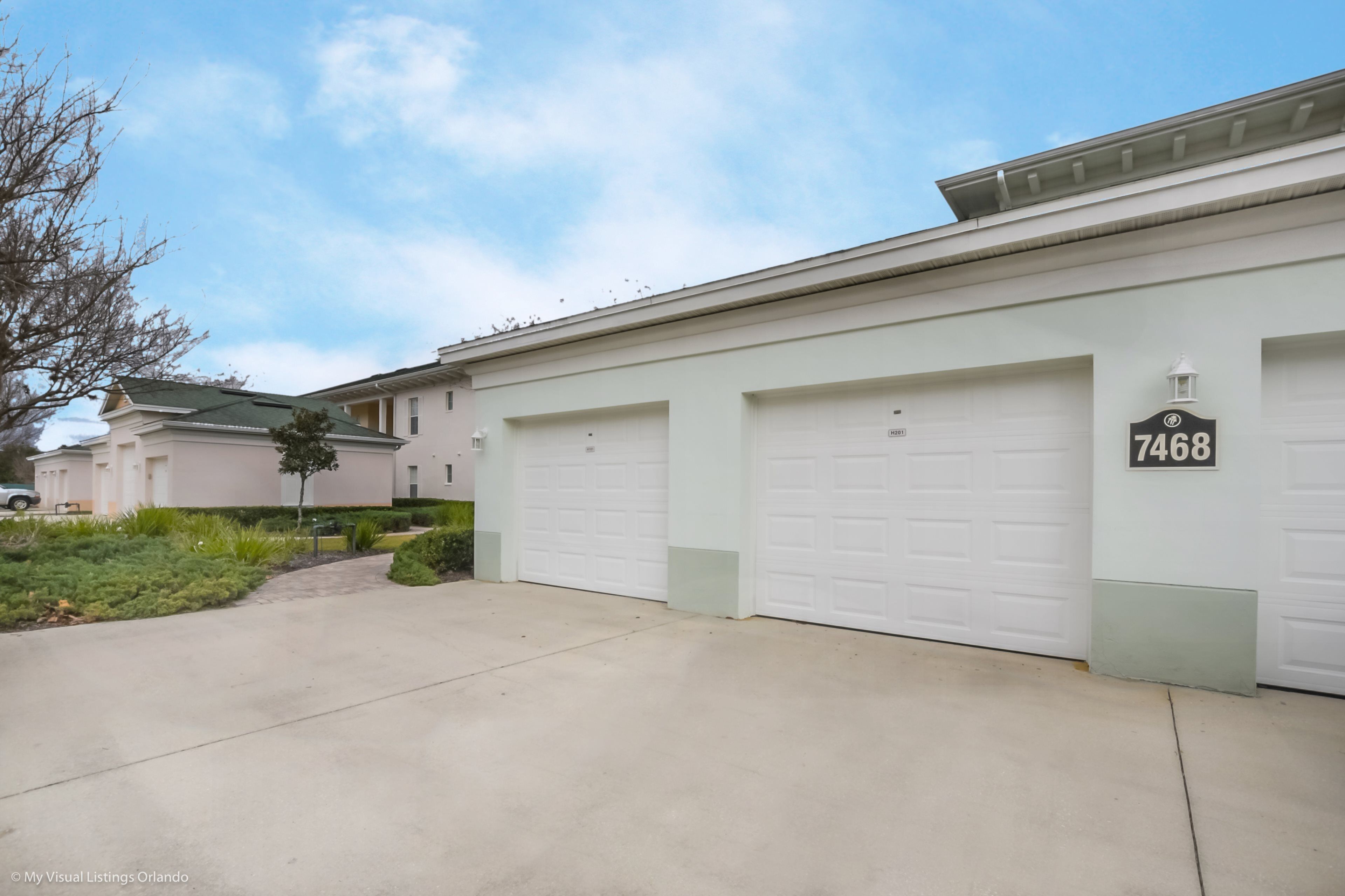A residential building with three garage doors, a well-maintained driveway, and a clear sky.