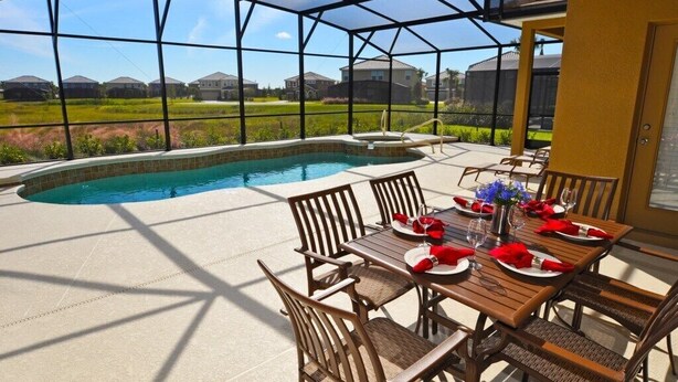 A covered outdoor area with a pool, dining table set for four, and chairs. - Solterra Resort IHR 3049 (Davenport)