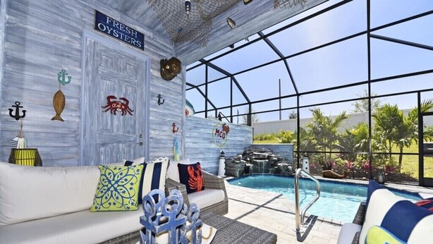 An indoor pool area with a glass ceiling, a white sofa with nautical-themed cushions, and a sign reading "FRESH OYSTERS". - Festival Resort IHR 3023 (Davenport)