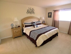 A bedroom with a large bed, two bedside tables, a wall clock, and a bicycle decoration. - Watersong Resort - 5 bed - Private Pool - IHR 3093 (Davenport)