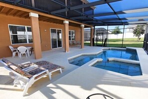 A covered outdoor swimming pool area with lounge chairs, a table, and a patio. - 110 Esspl (Davenport)
