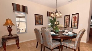 A dining room with a wooden table, floral chairs, a chandelier, and framed artwork on the walls. - 110 Esspl (Davenport)