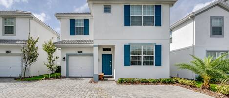 A modern two-story house with a front garage, blue shutters, and a well-maintained lawn.