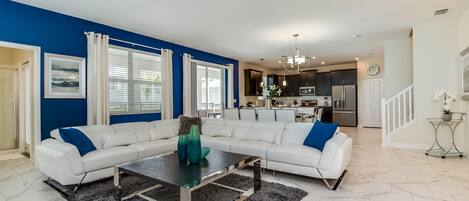 A modern living room with a sectional sofa, a coffee table, and a kitchen in the background.