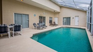 An indoor swimming pool with lounge chairs and a covered patio area. - West Haven IHR 4079 (Davenport)