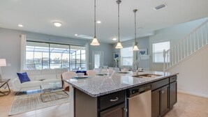 A modern kitchen with a central island, pendant lighting, and a view to the living area. - 5 Bed 5 Ba Home W Pool & Spa (Kissimmee)