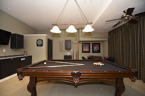 Relax in a stylish pool room with a pool table and comfortable seating area.