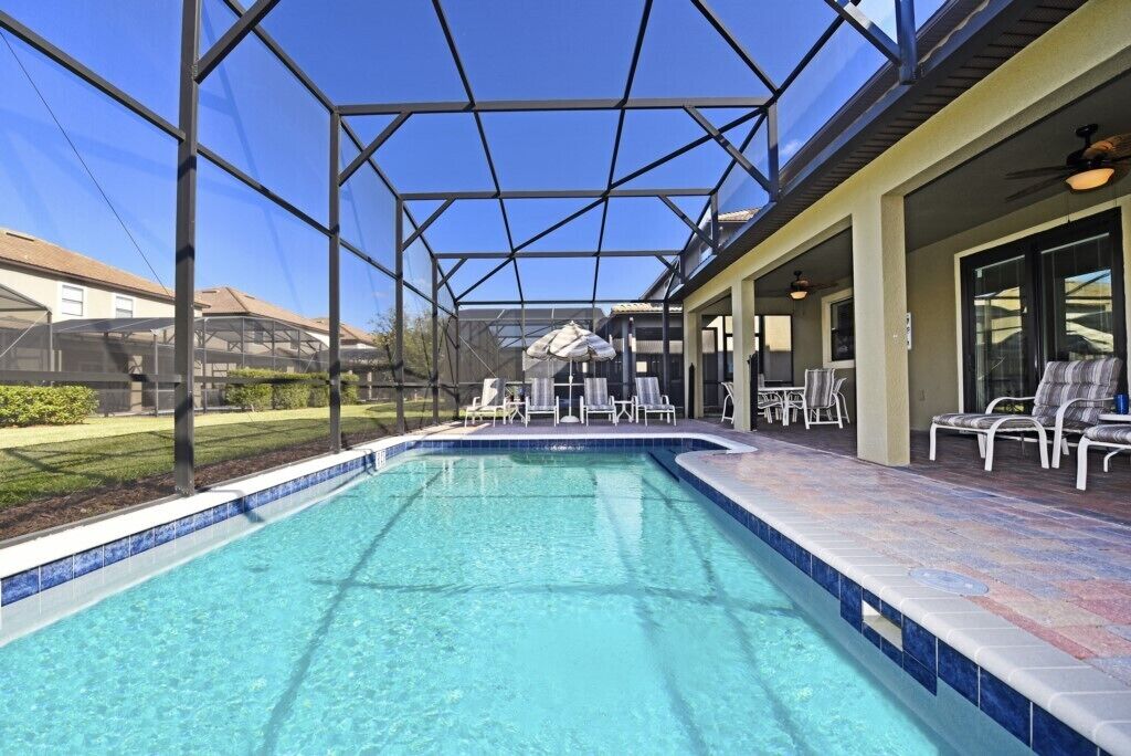 Una piscina exterior cubierta con agua azul cristalina, rodeada de sillones de descanso y una zona de terraza.